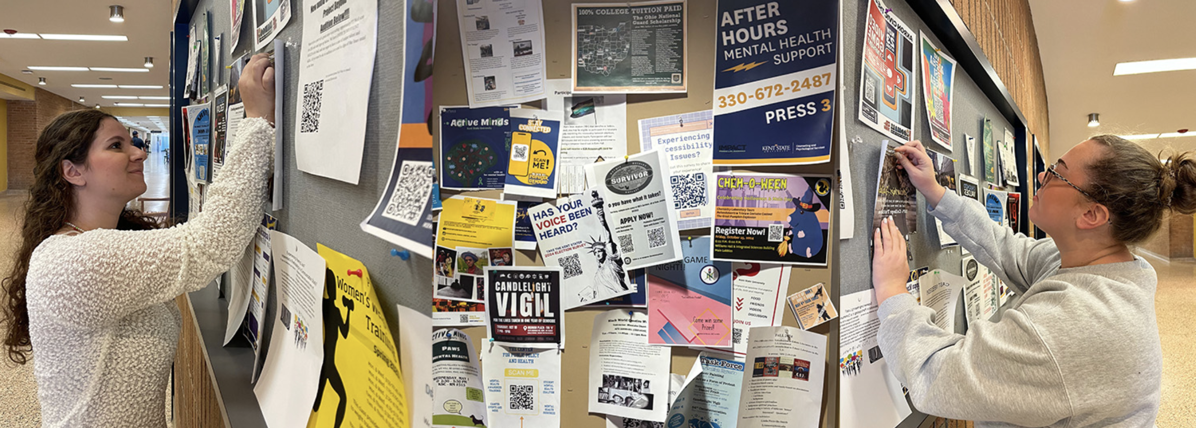 Students pin flyers to a bulletin board