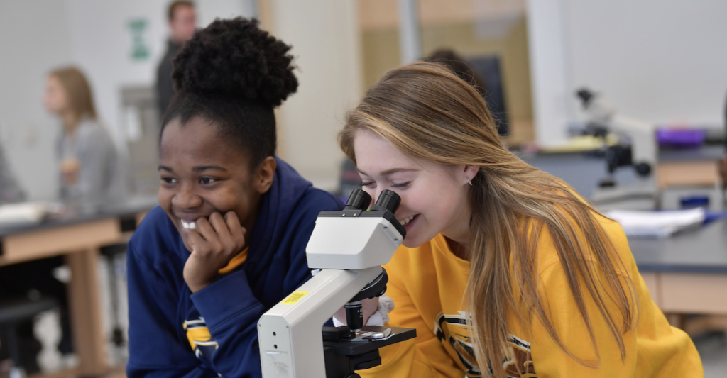 Two female students looking through a microscope